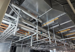 Fire-resistant custom steel support frame carrying combined M&E services beneath a roof.