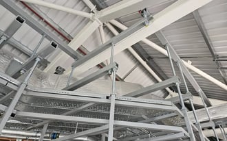 Suspended steel support frame and cable tray beneath a steel roof structure.